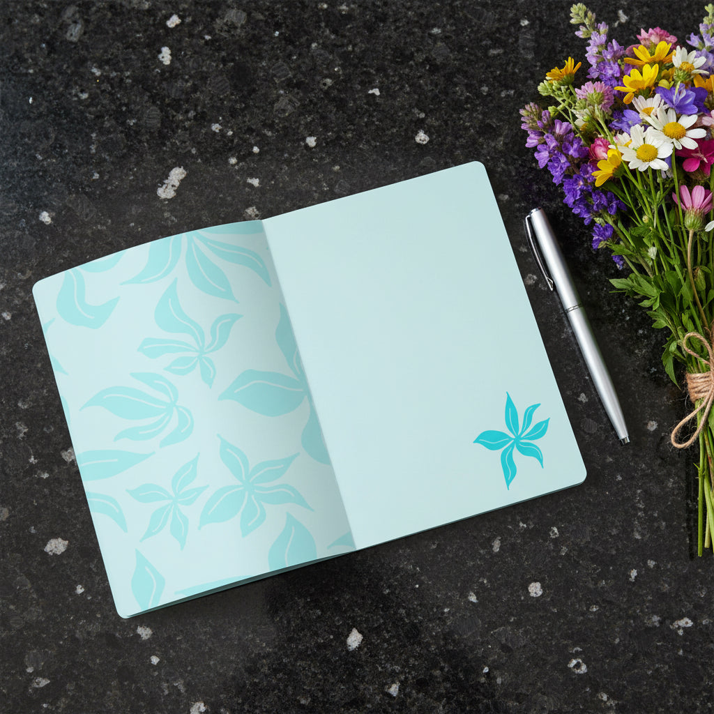 Light blue notebook with floral pattern and blank page showing, lying on a dark granite background with wildflowers bouquet.