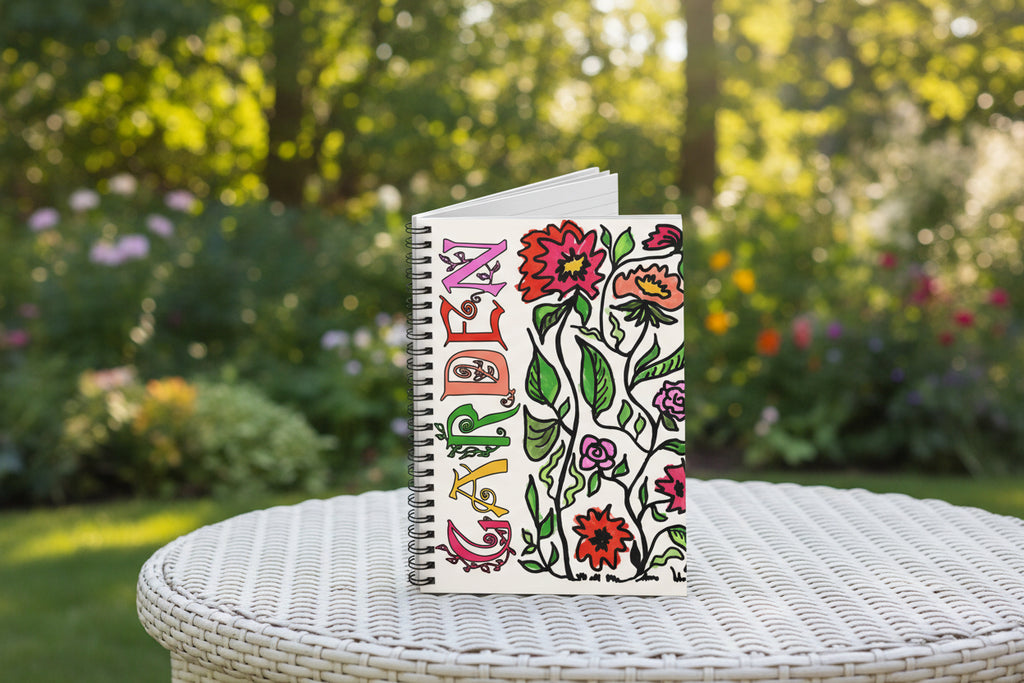 Notebook with colorful floral design and 'Garden' text sitting on a white table outside.