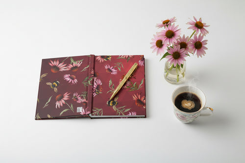 Floral notebook with pink coneflowers and bees on a red background